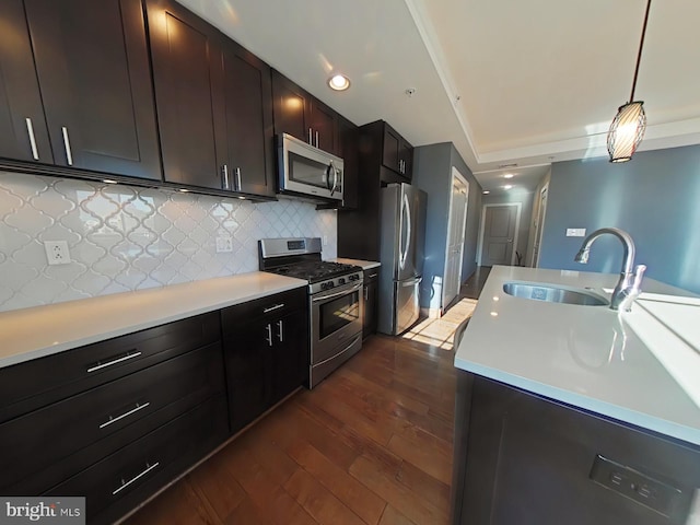 kitchen with sink, hanging light fixtures, dark wood-type flooring, decorative backsplash, and appliances with stainless steel finishes