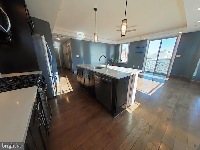 kitchen with appliances with stainless steel finishes, sink, a center island with sink, decorative light fixtures, and dark hardwood / wood-style floors