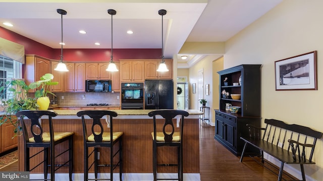 kitchen featuring a center island, black appliances, light stone counters, tasteful backsplash, and dark hardwood / wood-style flooring