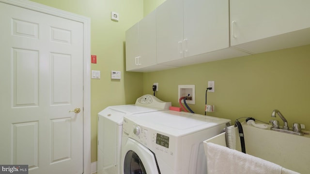 washroom with cabinets, sink, and washing machine and clothes dryer