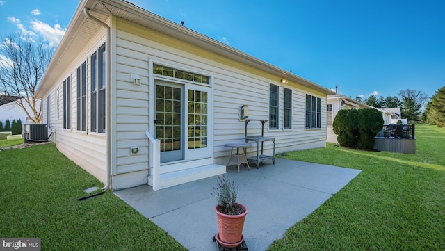 rear view of property featuring a yard, a patio, and central air condition unit