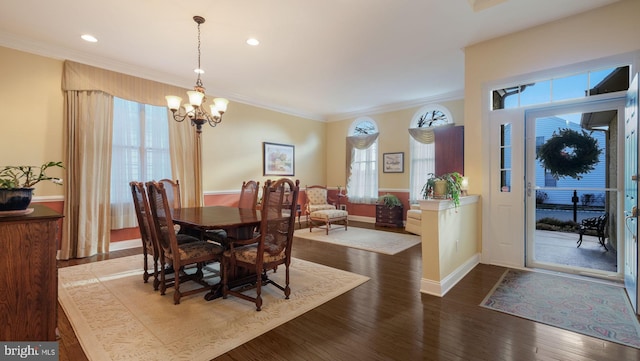 dining room with crown molding, dark wood-type flooring, and an inviting chandelier