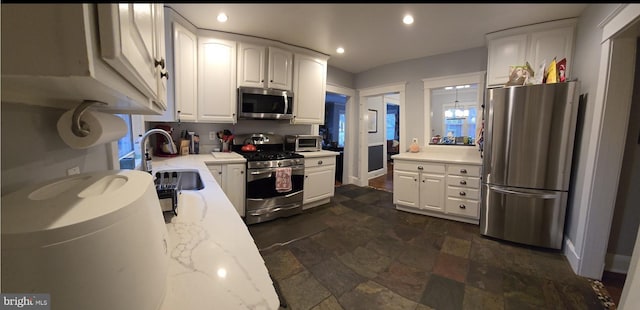 kitchen featuring appliances with stainless steel finishes, sink, white cabinets, and light stone counters