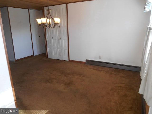 unfurnished dining area featuring a baseboard heating unit, dark colored carpet, a chandelier, and baseboards