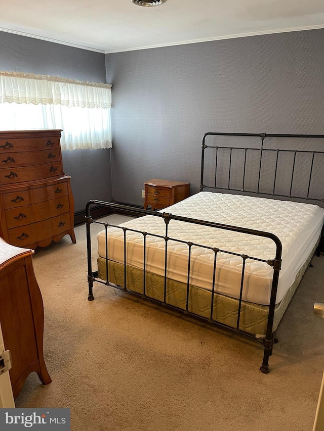 bedroom with ornamental molding and light colored carpet