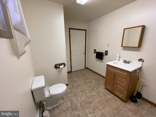 half bathroom with toilet, vanity, and baseboards