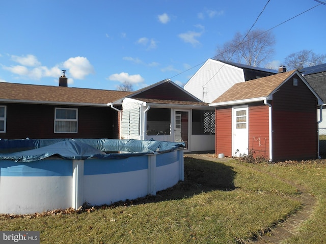 view of front of home with a chimney, a front yard, and a covered pool