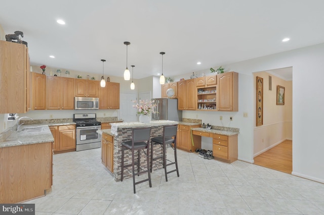 kitchen with light stone countertops, appliances with stainless steel finishes, a center island, and sink