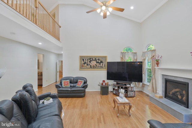 living room with crown molding, a fireplace, wood-type flooring, and a high ceiling