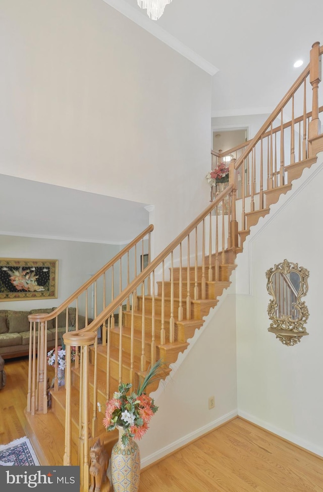 stairway featuring a chandelier, ornamental molding, and hardwood / wood-style flooring