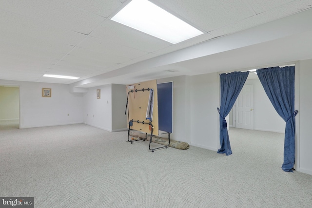 basement featuring a drop ceiling and light colored carpet