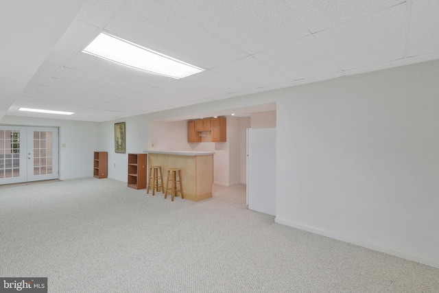 basement featuring white refrigerator, french doors, light carpet, and indoor bar