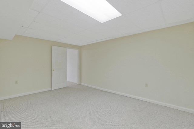 carpeted empty room featuring a drop ceiling