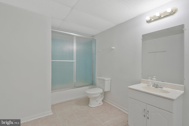 full bathroom featuring a drop ceiling, tile patterned floors, bath / shower combo with glass door, toilet, and vanity