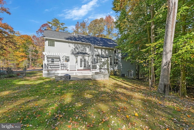 rear view of property featuring a lawn, a pergola, a patio, and a wooden deck