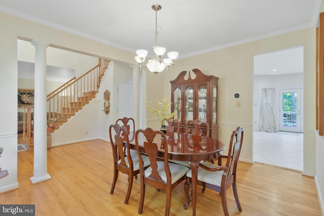 dining room with a notable chandelier, ornate columns, ornamental molding, and light hardwood / wood-style flooring