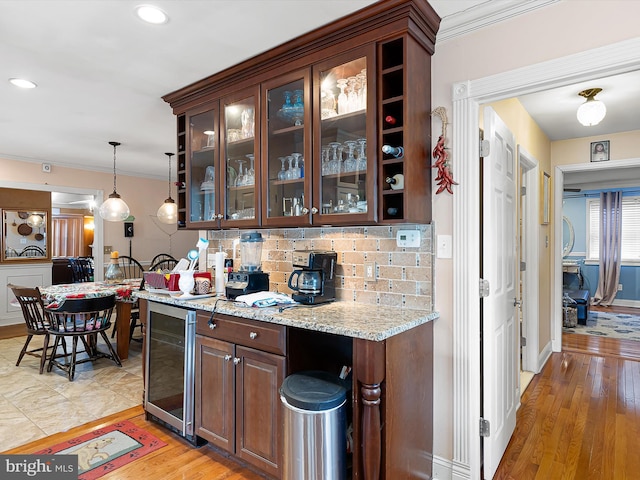 bar featuring decorative light fixtures, beverage cooler, decorative backsplash, light stone counters, and dark brown cabinets