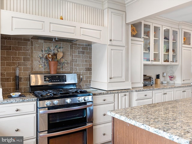 kitchen with white cabinetry, double oven range, and light stone counters