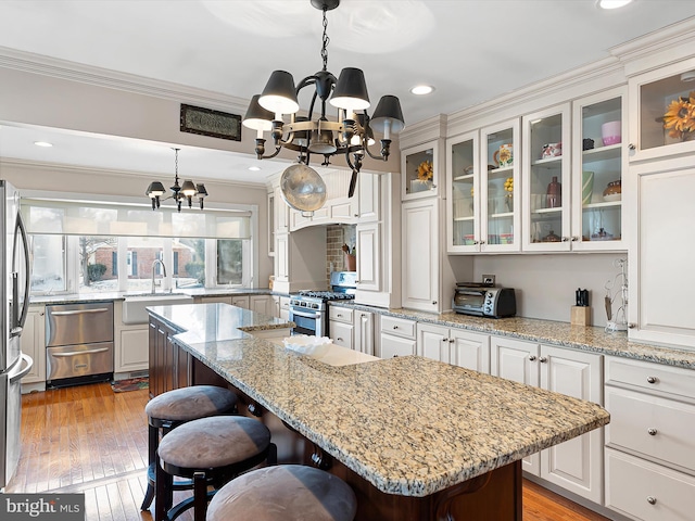 kitchen with a kitchen island, sink, a chandelier, hanging light fixtures, and stainless steel appliances