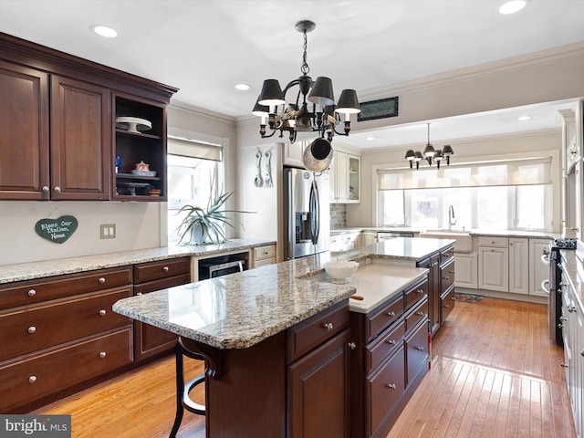 kitchen with sink, stainless steel appliances, a center island, a kitchen bar, and a chandelier