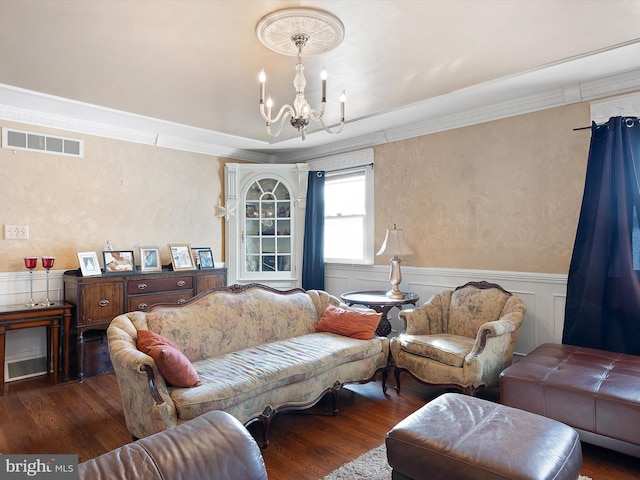 living room with dark hardwood / wood-style flooring, crown molding, and a chandelier