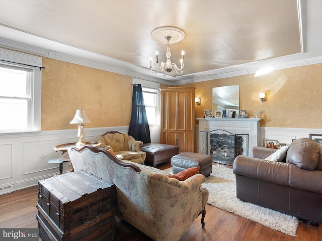 living room featuring hardwood / wood-style flooring, ornamental molding, and a chandelier