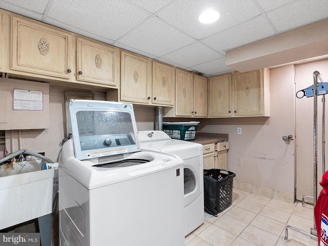 clothes washing area featuring cabinets, sink, light tile patterned floors, and washer and clothes dryer