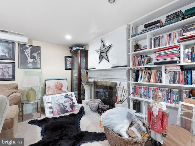 sitting room featuring a large fireplace and carpet flooring