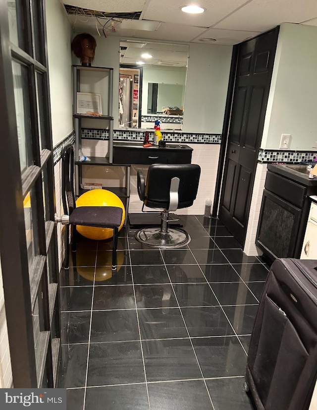 kitchen with a paneled ceiling, dark tile patterned flooring, and tile walls