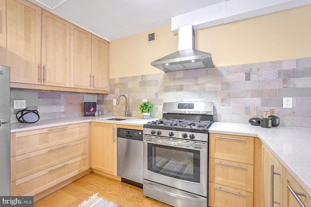 kitchen with wall chimney exhaust hood, light brown cabinets, stainless steel appliances, and tasteful backsplash