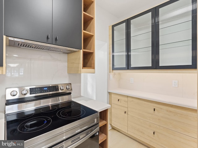 kitchen with stainless steel electric stove, decorative backsplash, and light brown cabinets