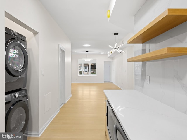 laundry area with stacked washer and dryer and light hardwood / wood-style flooring