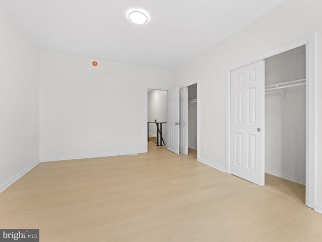 unfurnished bedroom featuring two closets and light wood-type flooring