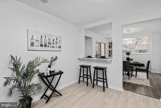 interior space with plenty of natural light, a kitchen breakfast bar, and light hardwood / wood-style flooring