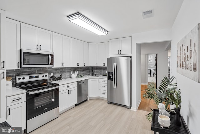 kitchen featuring sink, tasteful backsplash, stainless steel appliances, light hardwood / wood-style floors, and white cabinets