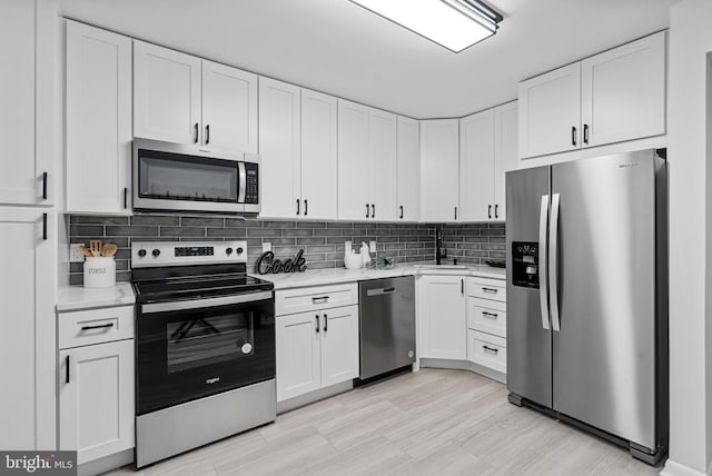 kitchen featuring backsplash, sink, white cabinets, and appliances with stainless steel finishes