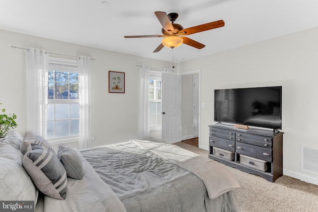 carpeted bedroom with multiple windows and ceiling fan