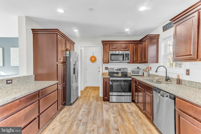 kitchen featuring light hardwood / wood-style floors, sink, light stone countertops, and stainless steel appliances