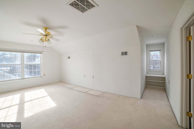 interior space with light carpet, ceiling fan, vaulted ceiling, and a healthy amount of sunlight