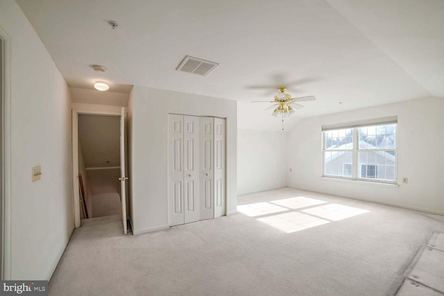 unfurnished bedroom featuring lofted ceiling, light colored carpet, a closet, and ceiling fan