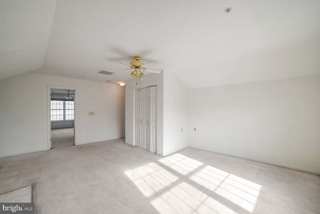 additional living space with vaulted ceiling, light colored carpet, and ceiling fan