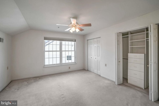 unfurnished bedroom featuring multiple closets, ceiling fan, light colored carpet, and vaulted ceiling