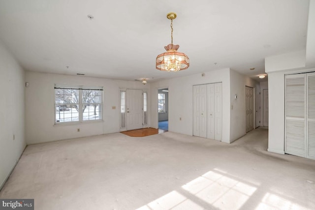 unfurnished living room featuring light colored carpet and a healthy amount of sunlight