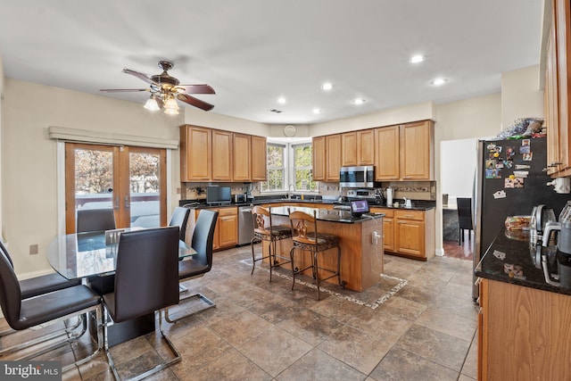 kitchen with french doors, a breakfast bar, sink, appliances with stainless steel finishes, and a kitchen island