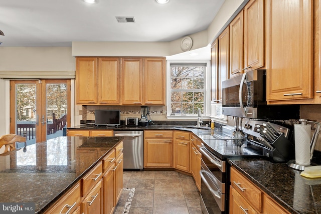 kitchen with stainless steel appliances, sink, and dark stone counters