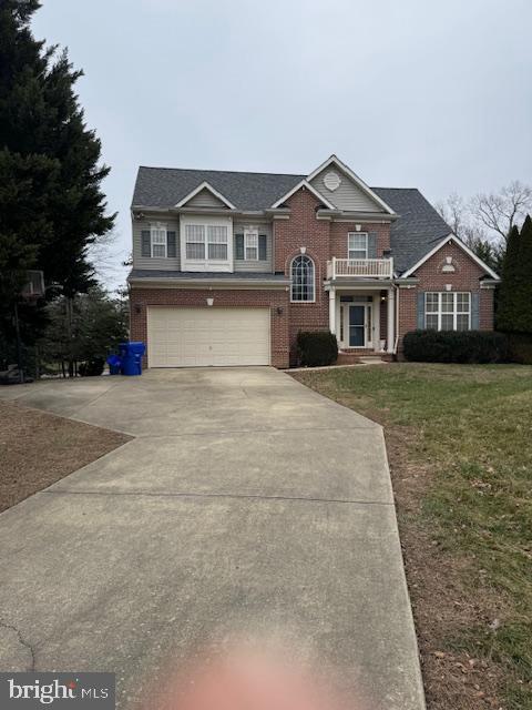 view of front of property featuring a garage, a front lawn, and a balcony