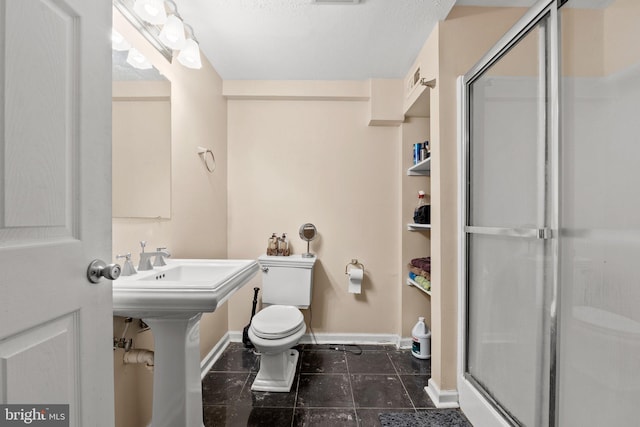 bathroom with toilet, sink, and a shower with shower door