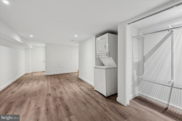 laundry room with stacked washer / dryer and light hardwood / wood-style flooring