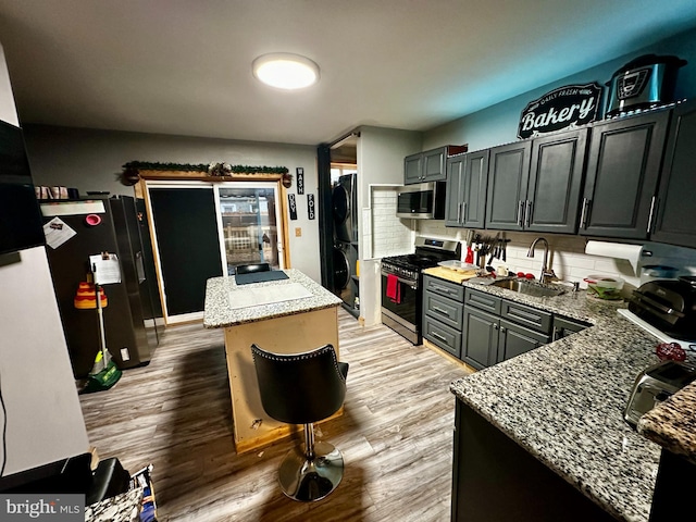 kitchen featuring sink, light stone countertops, stainless steel appliances, and light hardwood / wood-style flooring