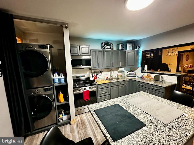 kitchen with decorative backsplash, appliances with stainless steel finishes, stacked washer and clothes dryer, and gray cabinetry